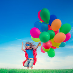 Superhero with toy balloons in spring field