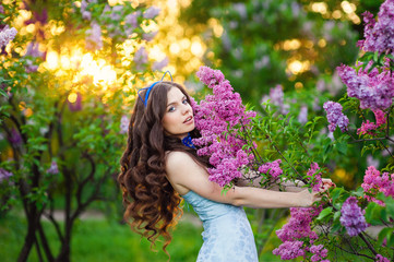 Beautiful young woman standing in the garden with a branch of li