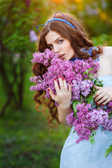 Beautiful young woman standing in the garden with a branch of li