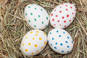 Fototapeta na wymiar four spotted colored easter eggs in hay