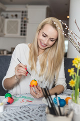 Beautiful young woman painting easter eggs