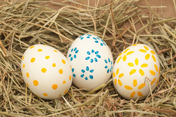 three spotted easter eggs on hay