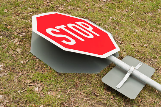 Verkehrsschild - Stopschild - liegt umgefallen auf dem Rasen