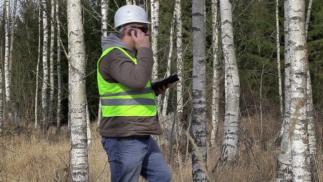Forest engineer talking on cell phone in birch grove