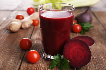 Glass of beet juice with vegetables on wooden table close up