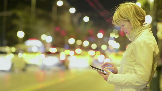 Woman working on tablet in the night city