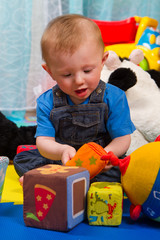 little boy playing with colored soft cube