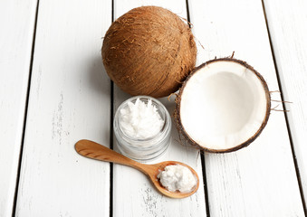 Coconut with coconut oil in jar on wooden background