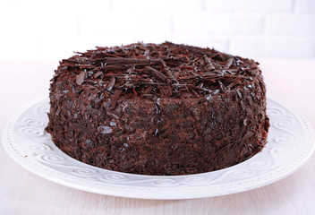 Tasty chocolate cake on table on brick wall background