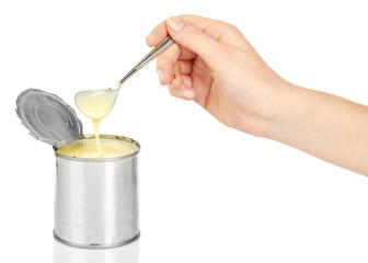 Tin can of condensed milk with spoon isolated on white
