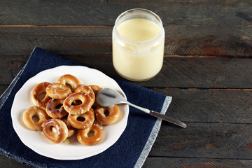 Bagels on plate with jar of condensed milk on wooden background