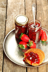 Jars of strawberry jam with berries and wafers