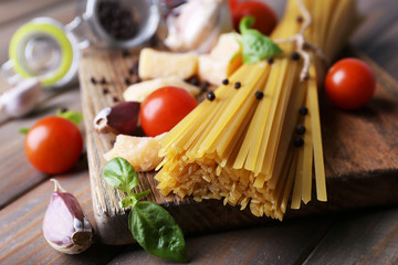 Raw pasta with cheese and vegetables on wooden background