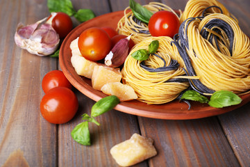 Raw pasta with cheese and vegetables on plate on table close up