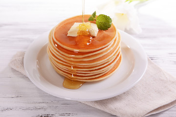 Delicious pancakes with honey on plate on table close-up
