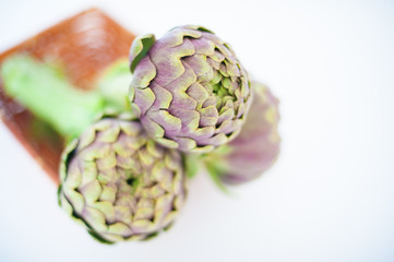 Bunch of three artichokes in basket on white background