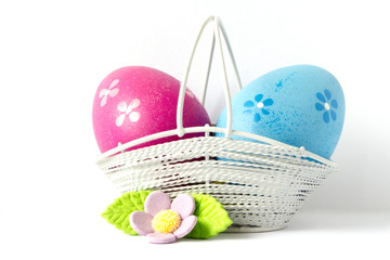 Pink and blue Easter eggs in a basket with lilac flower