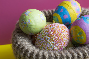 Fototapeta na wymiar Multi-colored Easter eggs in knitted basket
