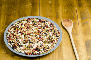 legumes in a dish on wood, with spoon, close up, background
