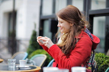 Young woman taking mobile photo of her cup of coffee