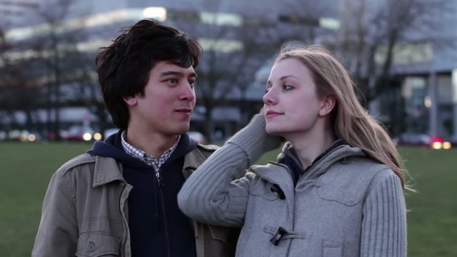 Good Looking Young Man And Woman In Conversation Against The Backdrop Of The City At Dusk.  Guy Uses Chapstick During This Clip.  Recorded In Downtown Portland, Oregon.