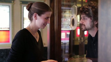 Young woman buys a ticket at a theater box office.  Dolly move which continues after she's left.