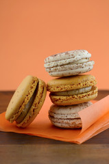 Caramel macaroons on orange and dark wood table.