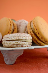 Caramel macaroons on orange and dark wood table.