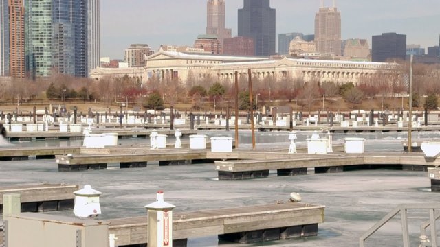 Boat breaking through ice in harbor along shoreline of Chicago