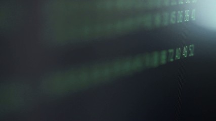 Detail of random computer code passing by on a screen.  Macro shot with focus pull and deliberate light flare.