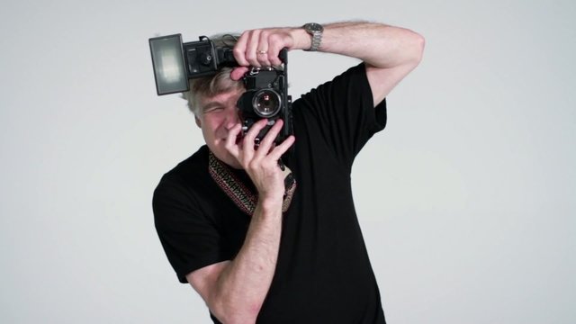 Photographer taking pictures in studio with SLR and flash.
