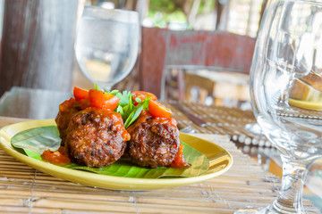 meat balls with tomato served on palm tree leaf