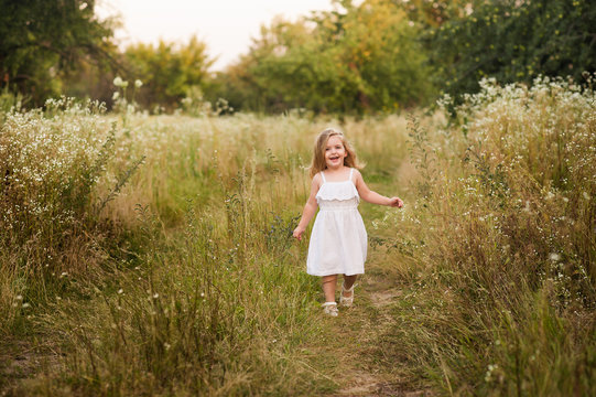 Маленькая девочка улыбается и идет в поле