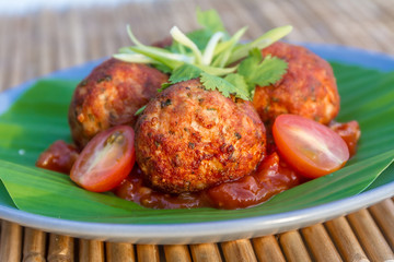 meat balls with tomato served on palm tree leaf