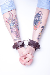 Tattooed Arms/tattooed arms with leather handcuffs on wrists