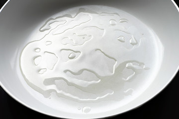 Cooking oil on white ceramic frypan.