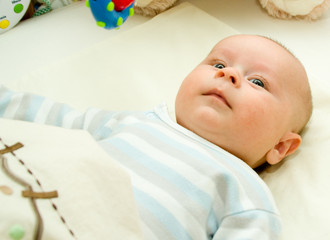 Infant boy laying and watching onto a bright toy