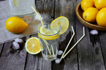 Lemonade in a transparent glass and lemons on a  wooden table