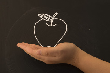 holding a apple in hand on blackboard