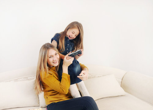 little girl with her mother playing TV video game device on the