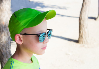 The child in a green baseball cap and sunglasses