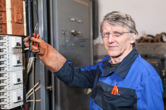 Electrcian maintainer holds pliers in hand wearing rubber glove