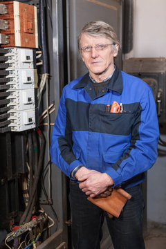 Senior man electrician in uniform stands near high voltage box