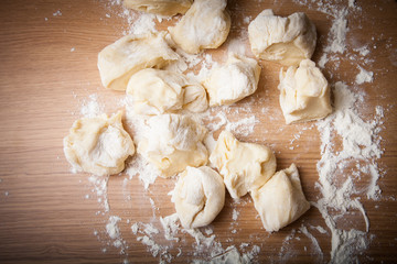 Fototapeta na wymiar Pieces of dough on floured wooden table
