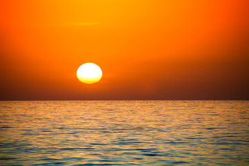 Fototapeta na wymiar Uneven disk of the sun setting over the horizon