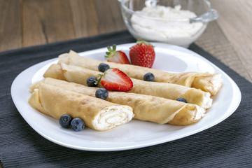 Delicious sweet rolled pancakes on a plate with fresh fruits