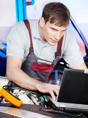 Motor mechanic is tuning the engine of a car