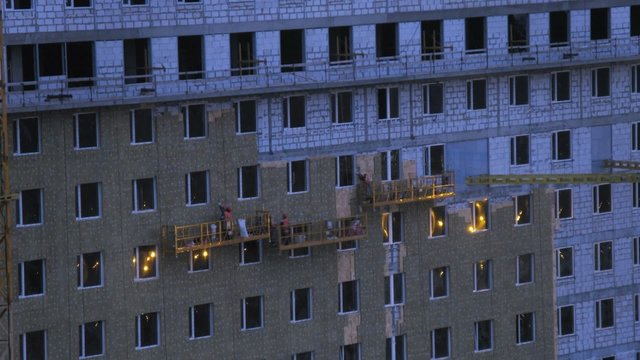 Workers making insulation high-rise building while evening. Timelapse