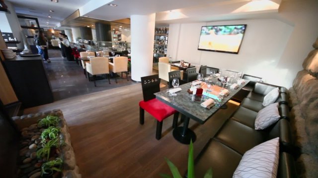 Manger and waiter meet several clients which come in restaurant with tv set on wall