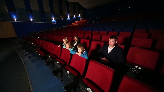 Family of five in a large empty cinema hall watching a movie